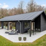 Black house with terrace, loungers, and garden. Modern design with large windows.