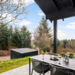 Patio with table and chairs, view of forest and sky.