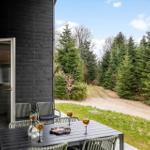 Terrace with table and chairs in front of a wooden house. View of forest and path.