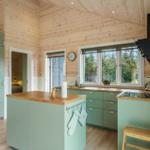 Kitchen with green cabinets, wooden countertop, and view of trees.