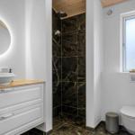Bathroom with shower, sink, and toilet. Wood and marble look.