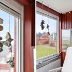 Fenster mit Steinanhänger und Sicht auf Haus und Grünfläche.