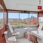Terrasse mit Sitzgelegenheiten und Blick auf rote Häuser.