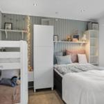 Schlafzimmer mit Doppelbett, Hochbett und weißen Regalen an der Wand.