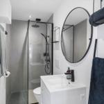 Badezimmer mit Dusche, Waschbecken und Spiegel