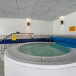 Innenpool mit Whirlpool und blauer Plane, Wand mit Schildern und Handlauf.