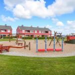 Roter Ferienhauskomplex mit Spielplatz und Grillplatz im Freien.