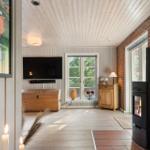 Wohnraum mit Kamin, TV und Fenster zum Garten