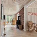 Haus mit Holzdecke, Backsteinwand und Schild zur Strandseite.