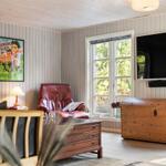 Ein Wohnzimmer mit rotem Ledersessel, Holzmöbeln und Fenster zur grünen Außenseite.