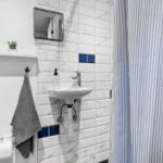 Badezimmer mit Waschbecken, Spiegel und Duschvorhang.