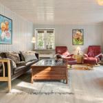 Wohnzimmer mit Sofa, zwei roten Sesseln, Couchtisch und Wandbildern.
