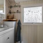 Bathroom with sink, mirror, and window with butterfly motif.