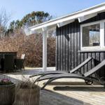 Terrace with lounge chairs, table and chairs. Black wooden wall and plants.