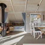 Living area with fireplace, sleeping area, and dining table. Wooden walls and ceiling.