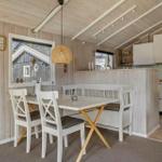 Dining area with table, chairs, and window. Kitchen area in background.