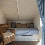 A bedroom with bed, pillows, chair, and fireplace.