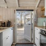 Kitchen with wooden wall, door to balcony, and white cabinets.