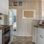 Kitchen with wooden walls, white cabinets, and wooden countertops. Passageway to another room.