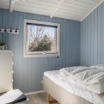 Bedroom with bed, window, and wood paneling.