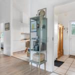 Entrance area with wooden floor, kitchen area, and glass display case with decorative items.