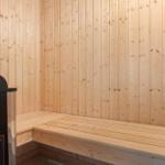 Sauna with wooden walls and bench. Heater on the left.