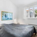 Bedroom with bed, window, and painting on the wall.