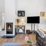 Living room with fireplace, TV, and sofa. Wooden floor and decorative items.