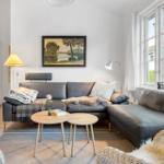 Living room with gray sofa, two round tables, and large window.