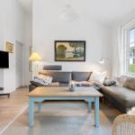 Living room with sofa, coffee table, and TV. Large windows with view of garden.
