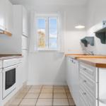 Kitchen with white cabinets, wooden surfaces, and window with view of trees.