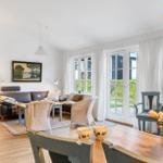 Living and dining area with sofa, tables, and windows to the garden.