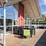 Deck with seating, swing, and sunshade. Wood deck and red siding visible.