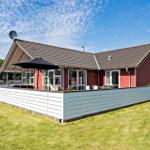 Red house with terrace, garden, and satellite dish under blue sky.