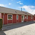 Red house with tiled roof and white door. Gravel yard and hedge.