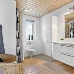 Bathroom with shower, toilet, sink, and wicker chair.