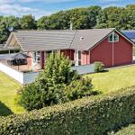 Red house with terrace and garden. Backyard with hedge and trees.