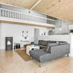 Living area with sofa, fireplace, and mezzanine. Kitchen with white cabinets.