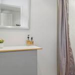 Bathroom with shower, sink, and mirror. Shower curtain and soap dispensers are visible.