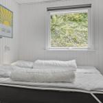 Bedroom with white bedding and window view of green plants.