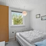 Bedroom with bed, window, and wooden wardrobe.