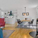 Living room with dining area, hardwood floor, and wood stove. Red seating and dining table with chairs.