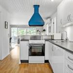 Kitchen with white cabinets, blue range hood, and hardwood floor.
