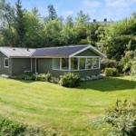 A green house with a large garden surrounded by trees.