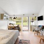 Bedroom with view of terrace and garden. White walls, wooden floor, and modern furnishings.