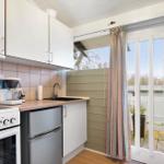 Kitchen with range hood, coffee maker, sink, and door to balcony.