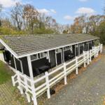 Long row of black holiday homes with white porches and tables.