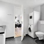 Bathroom with washing machine, toilet, and whirlpool tub.