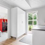 Entrance area with white cabinet and red coat rack. Passage to a room with red shelving.