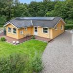 A yellow house with solar panels, terrace, and garden. Next to a gravel area is a carport.